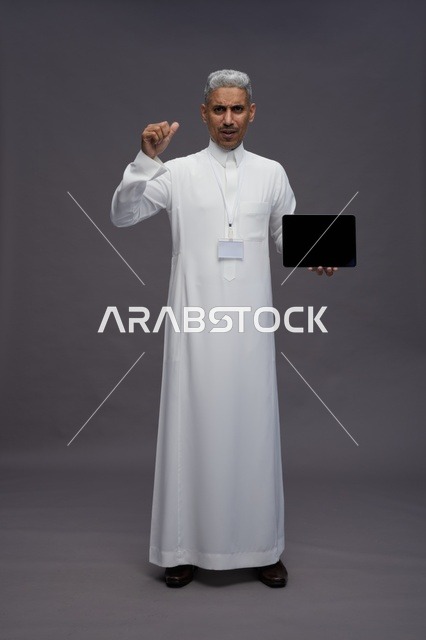 رجل سعودي يعرض جهازًا لوحيًا بشاشة فارغة