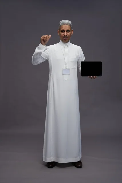 رجل سعودي يعرض جهازًا لوحيًا بشاشة فارغة