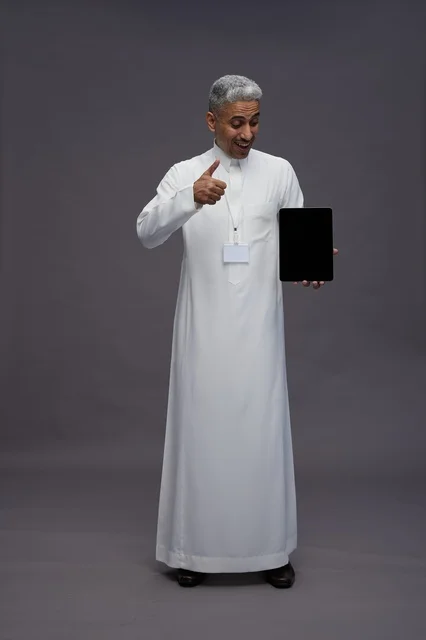 رجل سعودي يعرض جهازًا لوحيًا بشاشة فارغة