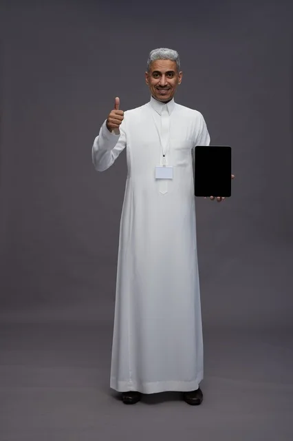 رجل سعودي يعرض جهازًا لوحيًا بشاشة فارغة