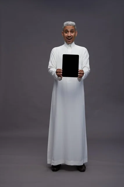 رجل سعودي يعرض جهازًا لوحيًا بشاشة فارغة
