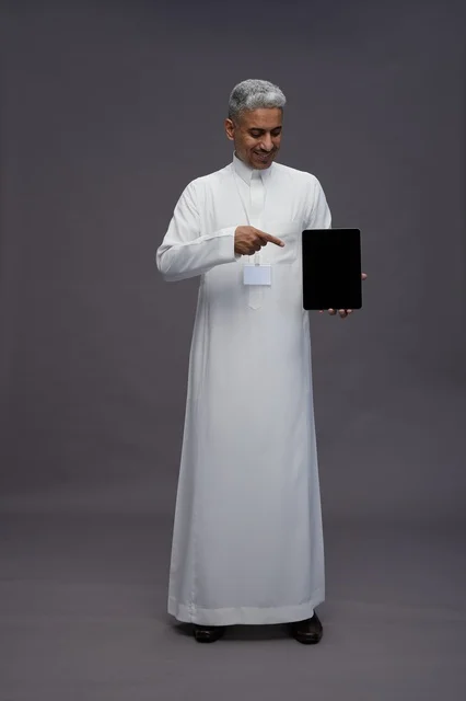 رجل سعودي يعرض جهازًا لوحيًا بشاشة فارغة