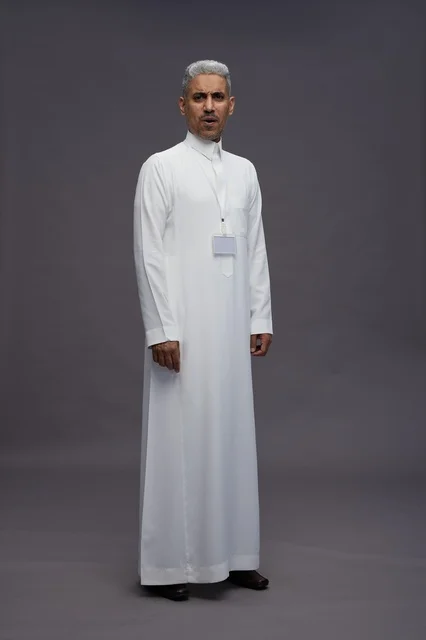 A portrait of a Saudi Arabian Gulf man wearing a white thobe, standing and making various gestures and signals in front of the camera, with a gray background, full body.