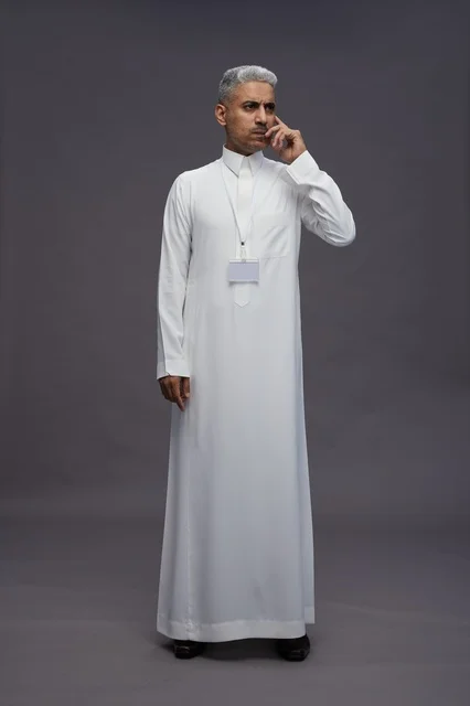 A portrait of a Saudi Arabian Gulf man wearing a white thobe, standing and making various gestures and signals in front of the camera, with a gray background, full body.