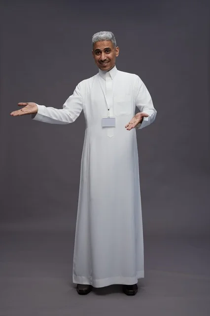 A portrait of a Saudi Arabian Gulf man wearing a white thobe, standing and making various gestures and signals in front of the camera, with a gray background, full body.
