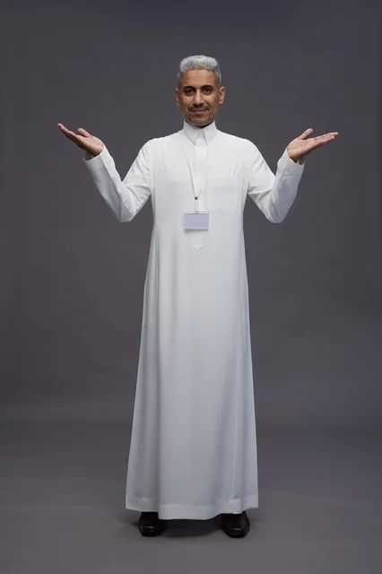 A portrait of a Saudi Arabian Gulf man wearing a white thobe, standing and making various gestures and signals in front of the camera, with a gray background, full body.