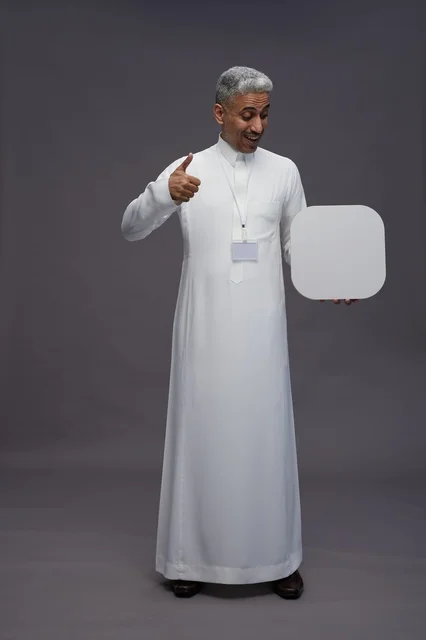A portrait of a Saudi Arabian Gulf man pointing to a blank white square board, a marketing advertisement board, full body, gray background.