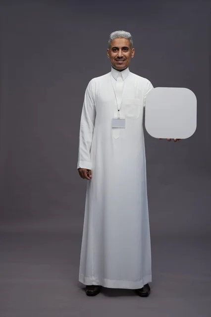 A portrait of a Saudi Arabian Gulf man pointing to a blank white square board, a marketing advertisement board, full body, gray background.