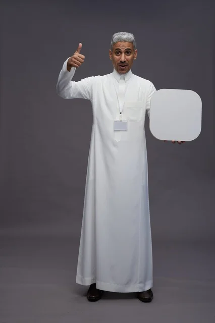A portrait of a Saudi Arabian Gulf man pointing to a blank white square board, a marketing advertisement board, full body, gray background.
