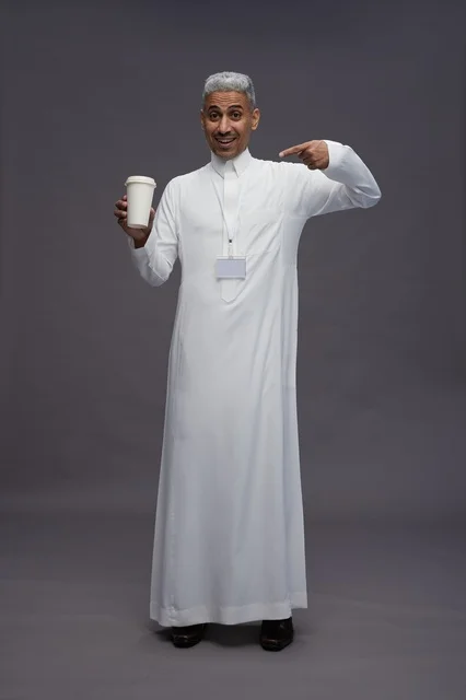 A portrait of an Arab Saudi Gulf man wearing a white thobe and enjoying drinking coffee, with a gray background, full body.