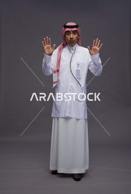 طبيب عربي سعودي خليجي يرتدي الثوب والمعطف الابيض مع سماعة الطب يقوم بايماءات واشارات مختلفه, كامل الجسم, خلفيه رماديه