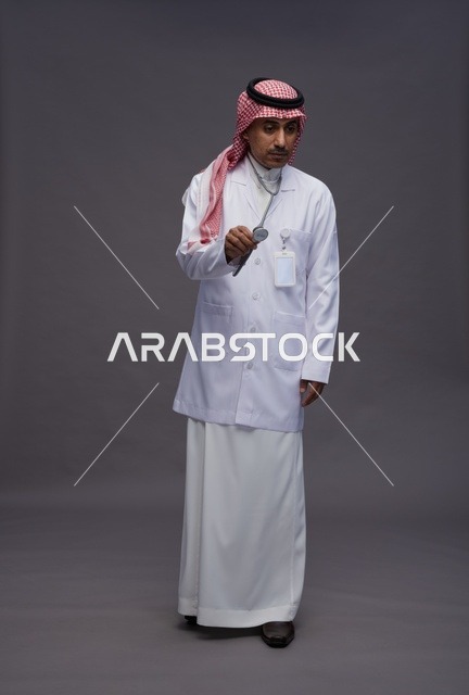 طبيب عربي سعودي خليجي يرتدي الثوب والمعطف الابيض مع سماعة الطب يقوم بايماءات واشارات مختلفه, كامل الجسم, خلفيه رماديه