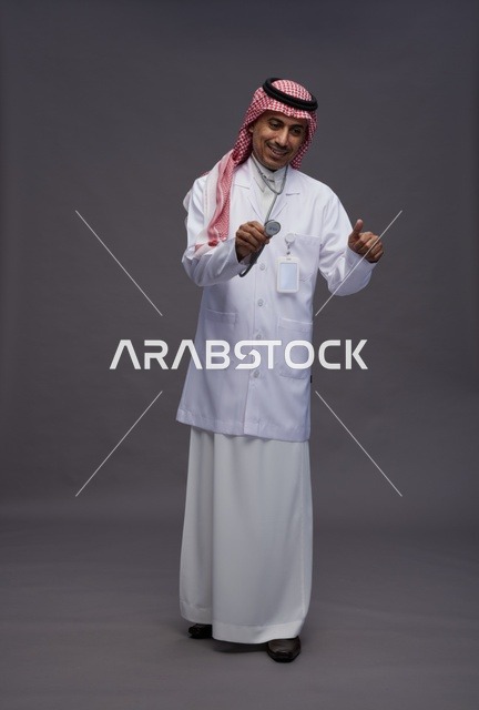 طبيب عربي سعودي خليجي يرتدي الثوب والمعطف الابيض مع سماعة الطب يقوم بايماءات واشارات مختلفه, كامل الجسم, خلفيه رماديه