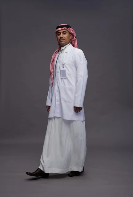 طبيب عربي سعودي خليجي يرتدي الثوب والمعطف الابيض مع سماعة الطب يقوم بايماءات واشارات مختلفه, كامل الجسم, خلفيه رماديه