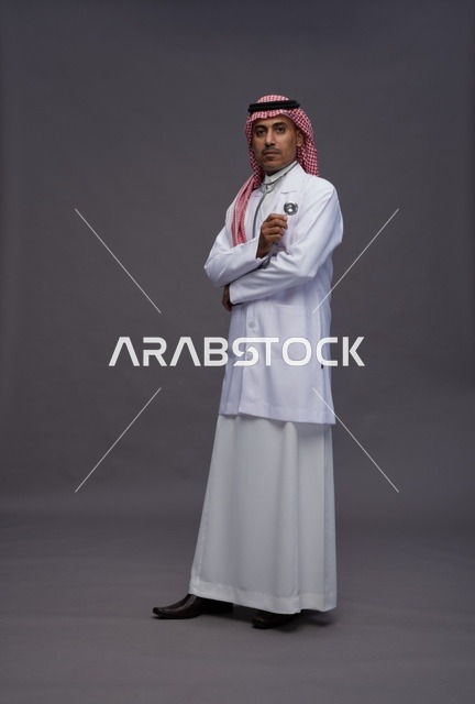 طبيب عربي سعودي خليجي يرتدي الثوب والمعطف الابيض مع سماعة الطب يقوم بايماءات واشارات مختلفه, كامل الجسم, خلفيه رماديه