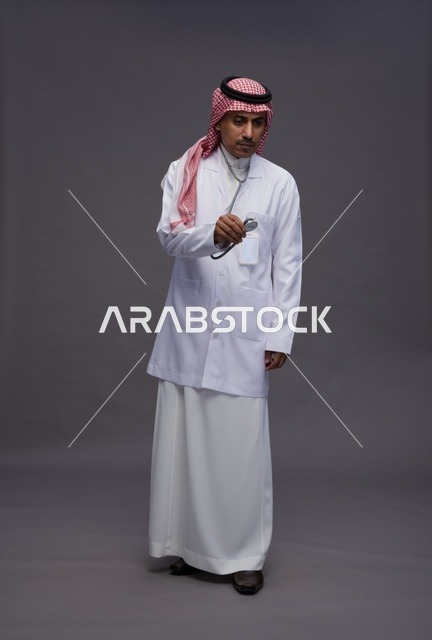طبيب عربي سعودي خليجي يرتدي الثوب والمعطف الابيض مع سماعة الطب يقوم بايماءات واشارات مختلفه, كامل الجسم, خلفيه رماديه