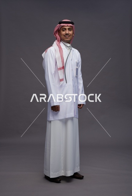 طبيب عربي سعودي خليجي يرتدي الثوب والمعطف الابيض مع سماعة الطب يقوم بايماءات واشارات مختلفه, كامل الجسم, خلفيه رماديه