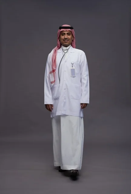 طبيب عربي سعودي خليجي يرتدي الثوب والمعطف الابيض مع سماعة الطب يقوم بايماءات واشارات مختلفه, كامل الجسم, خلفيه رماديه