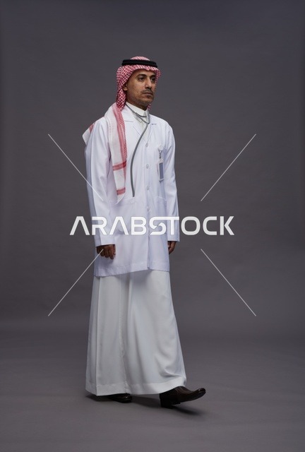 طبيب عربي سعودي خليجي يرتدي الثوب والمعطف الابيض مع سماعة الطب يقوم بايماءات واشارات مختلفه, كامل الجسم, خلفيه رماديه