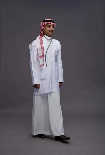 طبيب عربي سعودي خليجي يرتدي الثوب والمعطف الابيض مع سماعة الطب يقوم بايماءات واشارات مختلفه, كامل الجسم, خلفيه رماديه