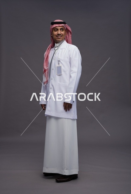 طبيب عربي سعودي خليجي يرتدي الثوب والمعطف الابيض مع سماعة الطب يقوم بايماءات واشارات مختلفه, كامل الجسم, خلفيه رماديه