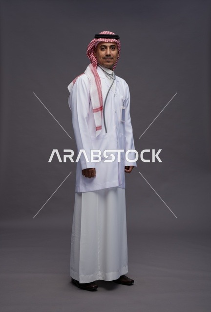 طبيب عربي سعودي خليجي يرتدي الثوب والمعطف الابيض مع سماعة الطب يقوم بايماءات واشارات مختلفه, كامل الجسم, خلفيه رماديه