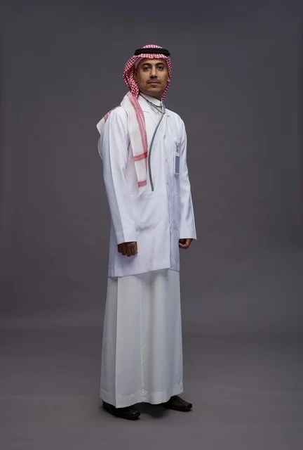 طبيب عربي سعودي خليجي يرتدي الثوب والمعطف الابيض مع سماعة الطب يقوم بايماءات واشارات مختلفه, كامل الجسم, خلفيه رماديه