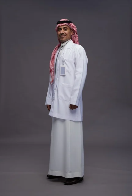 طبيب عربي سعودي خليجي يرتدي الثوب والمعطف الابيض مع سماعة الطب يقوم بايماءات واشارات مختلفه, كامل الجسم, خلفيه رماديه