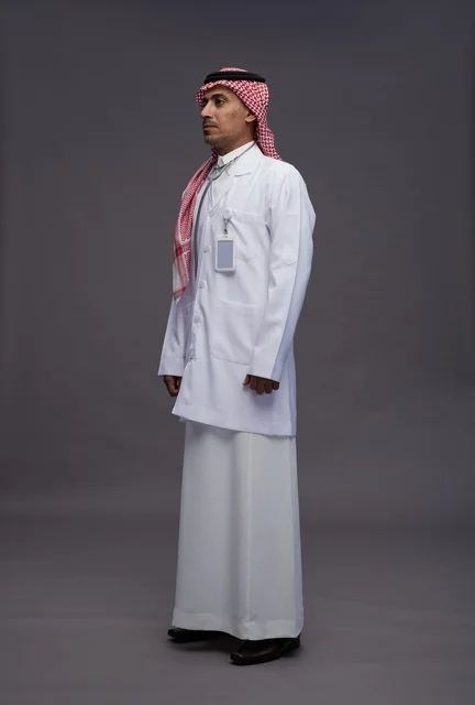 طبيب عربي سعودي خليجي يرتدي الثوب والمعطف الابيض مع سماعة الطب يقوم بايماءات واشارات مختلفه, كامل الجسم, خلفيه رماديه