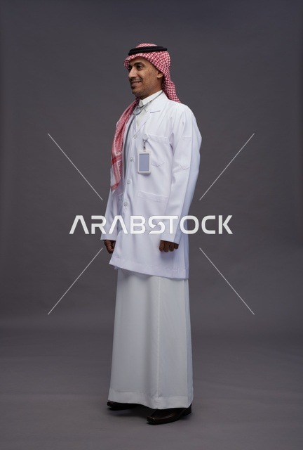 طبيب عربي سعودي خليجي يرتدي الثوب والمعطف الابيض مع سماعة الطب يقوم بايماءات واشارات مختلفه, كامل الجسم, خلفيه رماديه