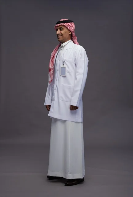 طبيب عربي سعودي خليجي يرتدي الثوب والمعطف الابيض مع سماعة الطب يقوم بايماءات واشارات مختلفه, كامل الجسم, خلفيه رماديه