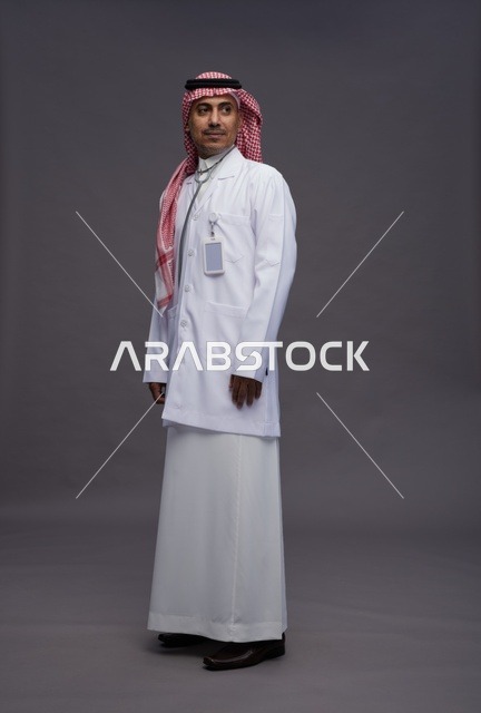 طبيب عربي سعودي خليجي يرتدي الثوب والمعطف الابيض مع سماعة الطب يقوم بايماءات واشارات مختلفه, كامل الجسم, خلفيه رماديه
