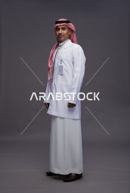 طبيب عربي سعودي خليجي يرتدي الثوب والمعطف الابيض مع سماعة الطب يقوم بايماءات واشارات مختلفه, كامل الجسم, خلفيه رماديه