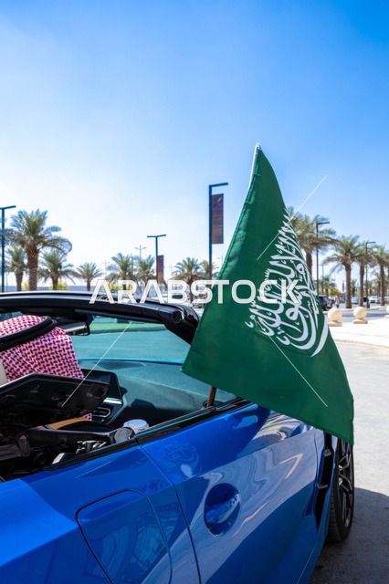 علم السعودية على سيارة زرقاء في اليوم الوطني