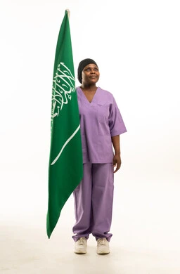 ممرضة أفريقية مع علم السعودية بالزي الطبي