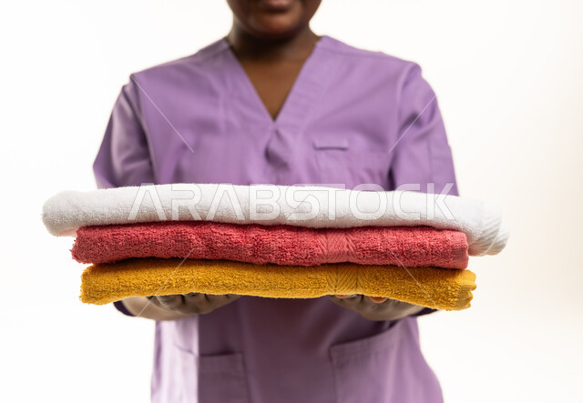 African Domestic Worker Holding Stack of Towels