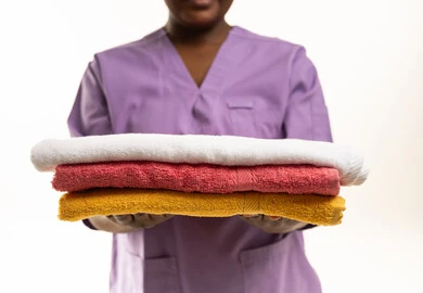African Domestic Worker Holding Stack of Towels
