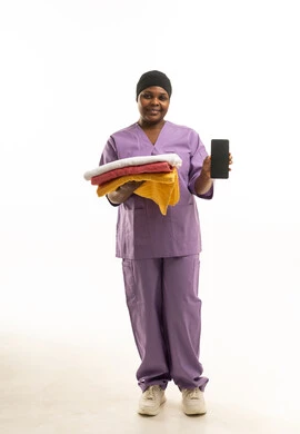 ممرضة أفريقية بالزي الأرجواني تحمل مناشف وهاتف