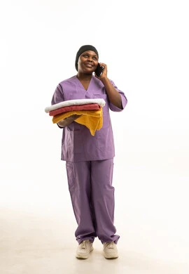 Black Nurse in Purple Scrubs Holding Towels on Phone
