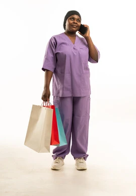 ممرضة بالزي الطبي تحمل حقائب تسوق وتتحدث بالهاتف