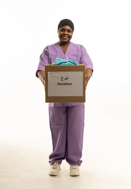 امرأة بزي طبي تحمل صندوق تبرعات بملابس