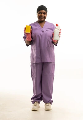 عاملة نظافة تحمل إسفنجة ومنظف بزي العمل