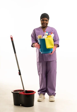 African Female Cleaner Holding Supplies in Purple Scrubs