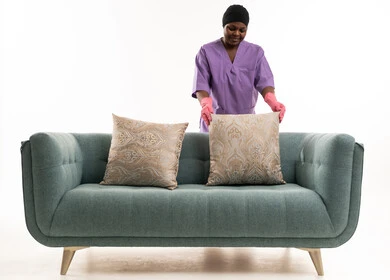 عاملة منزلية أفريقية ترتب الوسائد على الأريكة