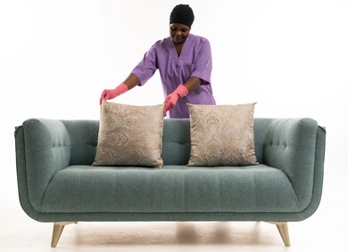 عاملة منزلية أفريقية ترتب وسائد الأريكة