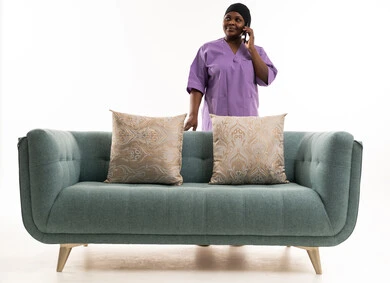 عاملة منزلية أفريقية تتحدث بالهاتف خلف الأريكة