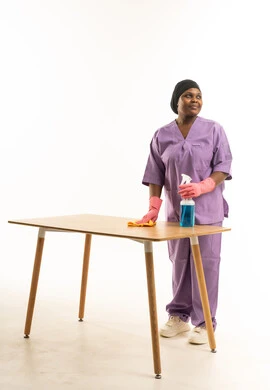 عاملة نظافة أفريقية تنظف طاولة خشبية في الاستوديو