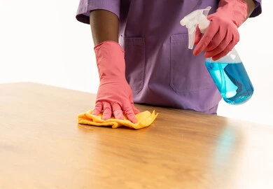 عامل من أصول أفريقية ينظف طاولة خشبية بالبخاخ