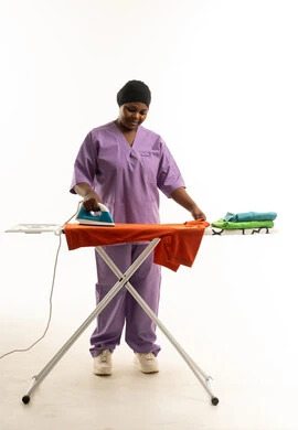 عاملة منزلية سعودية تقوم بكوي الملابس بخلفية بيضاء عاملة منزلية سعودية تقوم بكوي الملابس بخلفية بيضاء