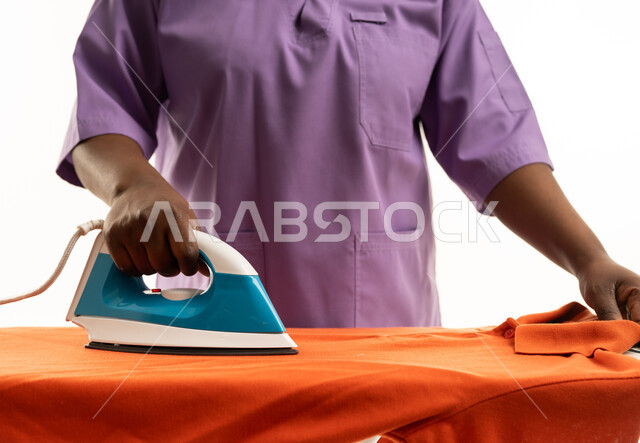 عاملة منزلية تقوم بكي الملابس بالزي الرسمي